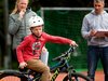 Un bambino in bici con il casco completa una gincana assistito da adulti