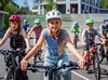 Un gruppo di studenti pedala nella stessa direzione. Una ragazza bionda è davanti a tutti, al centro.