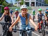 Un gruppo di studenti pedala nella stessa direzione. Una ragazza bionda è davanti a tutti, al centro.