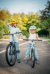 Due bambine sorridenti cercano di mantenere l’equilibrio in sella alla bici