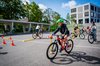 Mehrere Kinder fahren auf dem Schulgelände einen Veloparcours ab