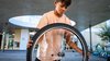 Un alunno tiene in mano la ruota di una bicicletta, presumibilmente per ripararla.
